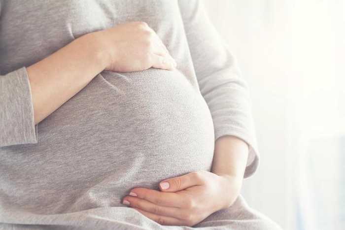 Pregnant person resting their hands on their belly