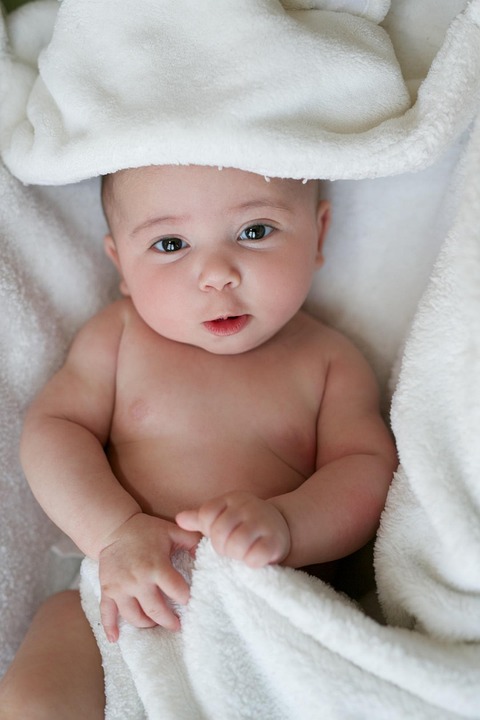 Awake baby wrapped in a white towel