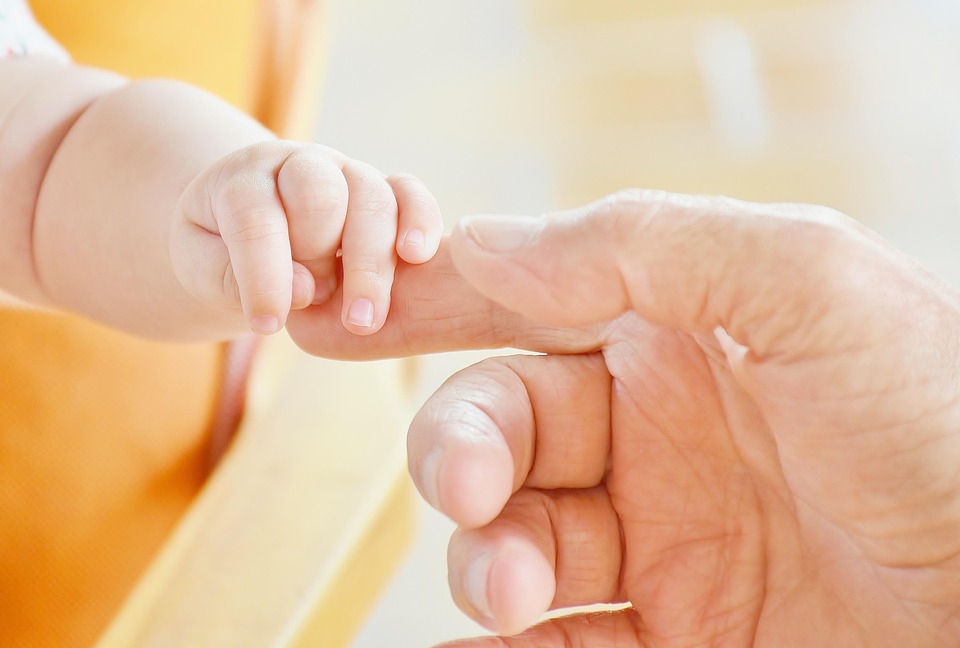 Baby holding an adult finger